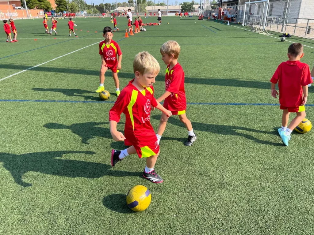 Niño pequeño aprendiendo a jugar al fútbol en el nivel de iniciación de fútbol